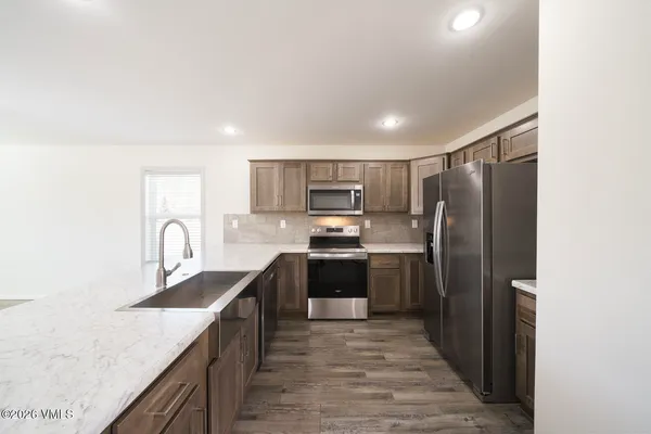 a kitchen with kitchen island granite countertop stainless steel appliances cabinets a sink and a counter top space