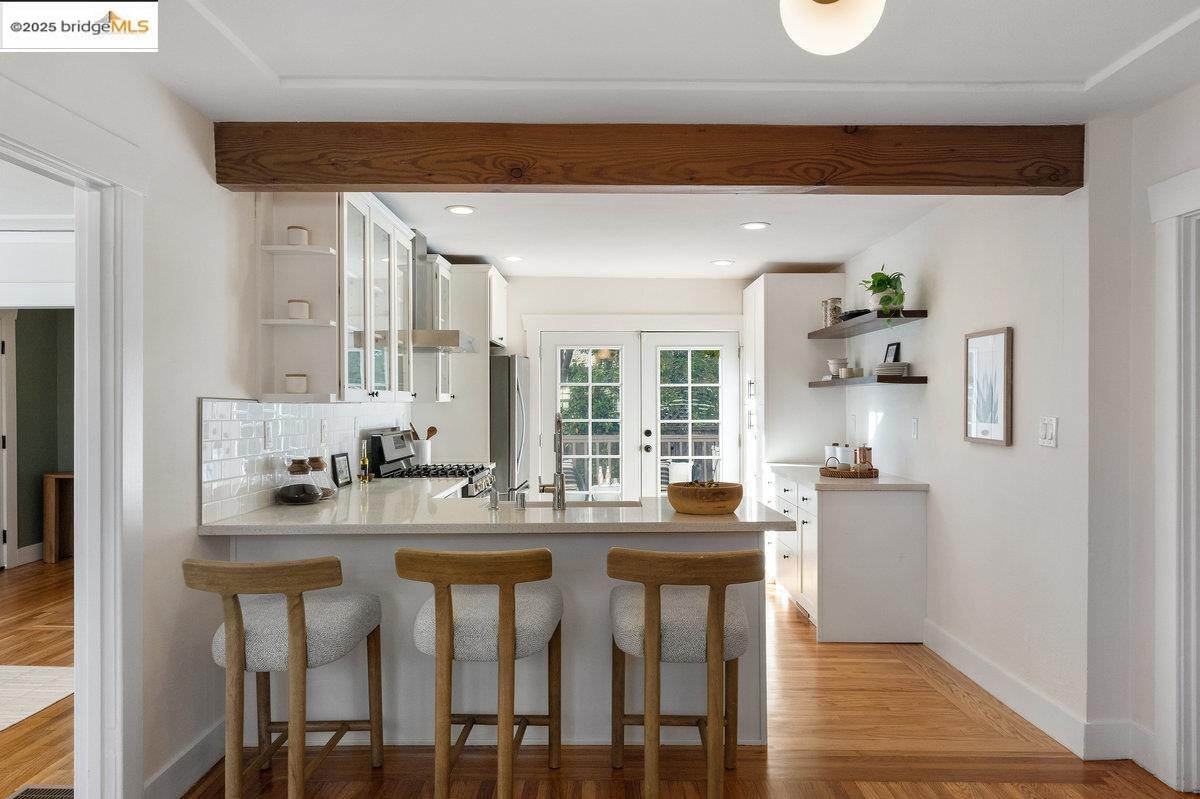 3056 California Street Oakland, CA 94602 - Photo 13 of 44 Kitchen with open shelves, a breakfast bar area, a peninsula, white cabinetry, and backsplash