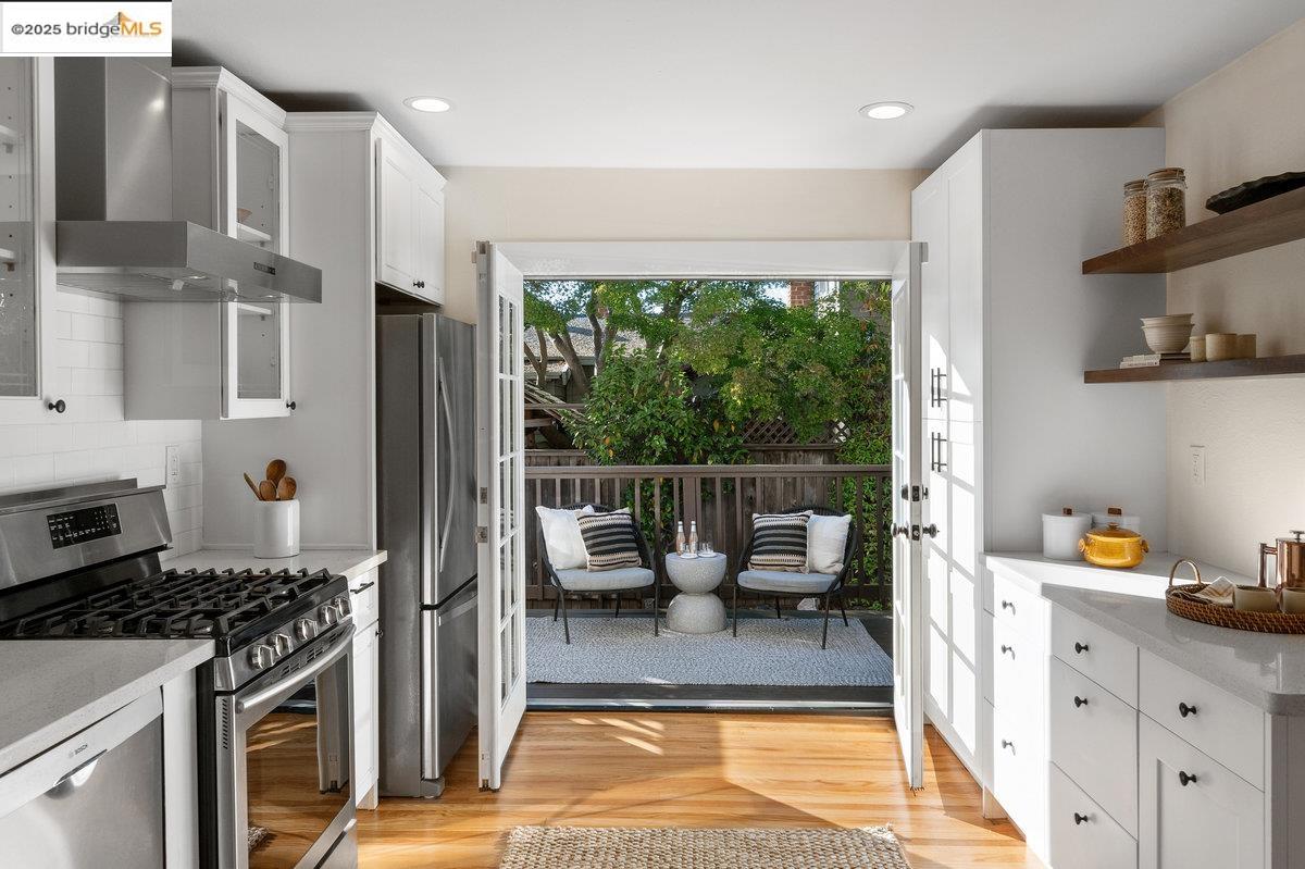 3056 California Street Oakland, CA 94602 - Photo 17 of 44 Kitchen featuring appliances with stainless steel finishes, wall chimney exhaust hood, white cabinetry, light wood-style floors, and recessed lighting
