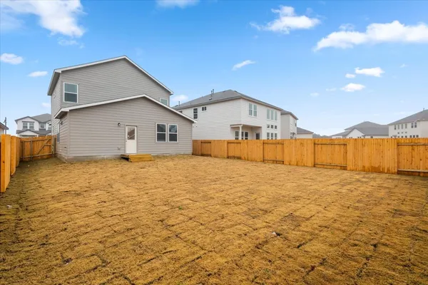 a view of a house with backyard and wooden fence