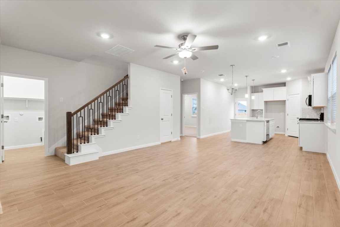 320 Windstar Road Liberty Hill, TX 78642 - Photo 4 of 29 a view of an empty room and kitchen view with wooden floor and staircase