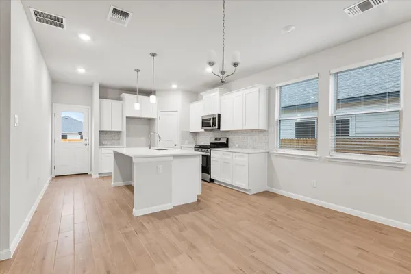 a kitchen with stainless steel appliances a refrigerator a stove a microwave and white cabinets