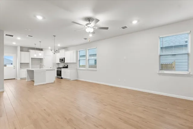 a view of an empty room with kitchen view and a window