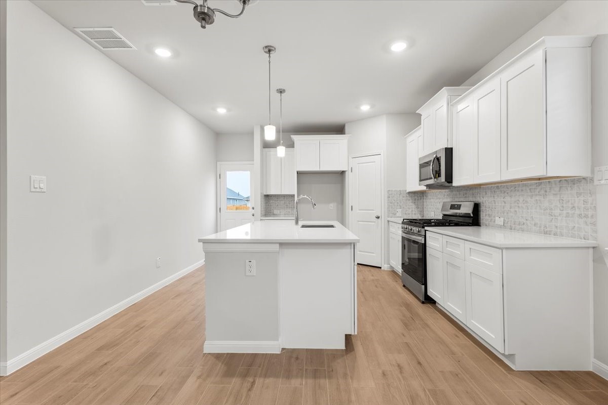 320 Windstar Road Liberty Hill, TX 78642 - Photo 8 of 29 a kitchen with stainless steel appliances granite countertop a sink a stove a refrigerator and white cabinets with wooden floor