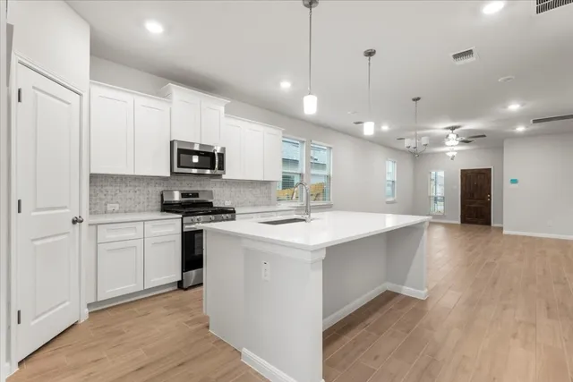 a kitchen with kitchen island a sink stainless steel appliances and cabinets