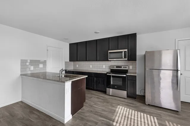 a kitchen with granite countertop a stove a sink and a microwave