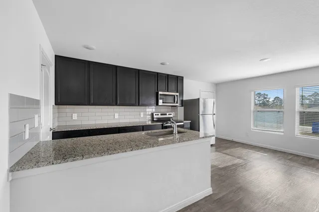 a kitchen with stainless steel appliances granite countertop a sink a stove and cabinets