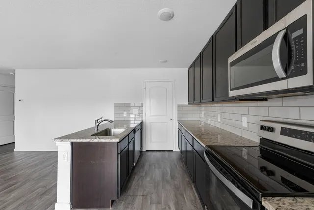 a kitchen with granite countertop a sink and a stove