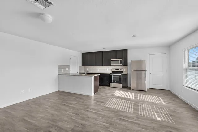 a view of a kitchen with wooden floor and electronic appliances
