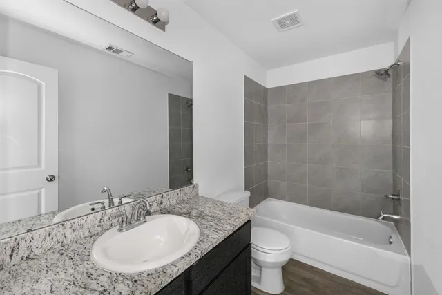 a bathroom with a granite countertop sink a toilet a mirror and bathtub