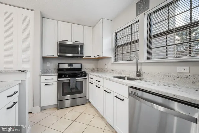 a kitchen with granite countertop a sink stainless steel appliances and cabinets