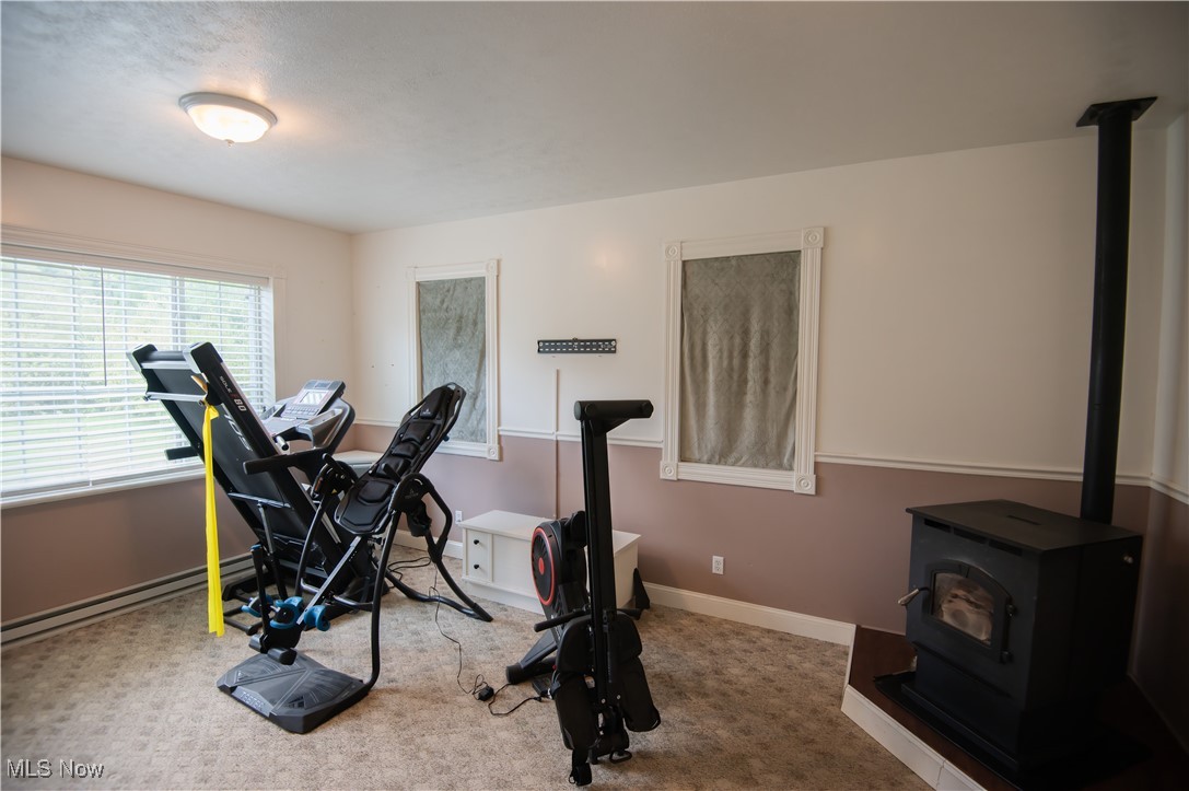 4594 Center Road Andover, OH 44003 - Photo 28 of 39 Exercise room with a wood stove, carpet, and a baseboard heating unit. 4th bedroom
