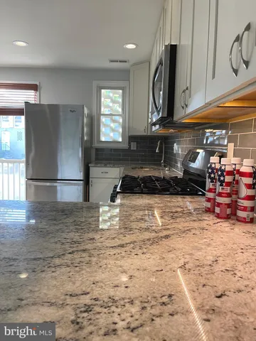 a kitchen with granite countertop a sink stove and refrigerator