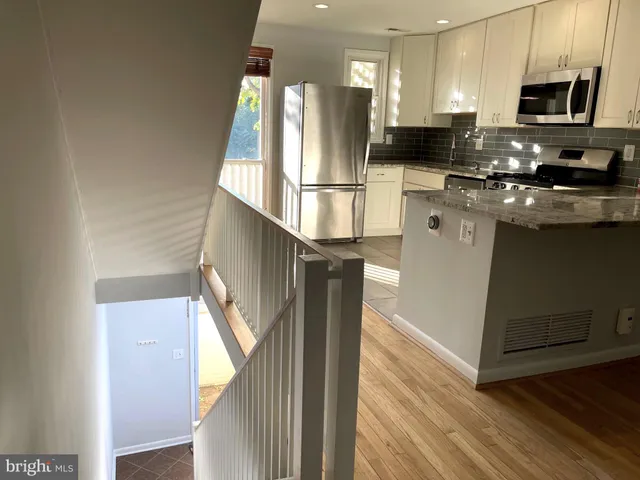 a kitchen with stainless steel appliances granite countertop a refrigerator a stove and a sink with wooden floor