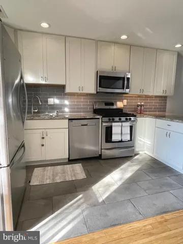 a kitchen with granite countertop a refrigerator stove and microwave