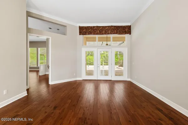 a view of an empty room with wooden floor and a window