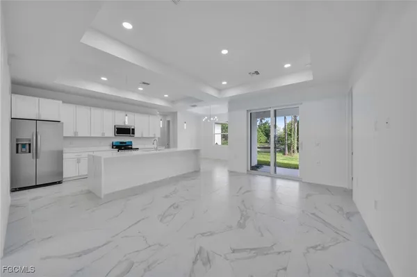 a large white kitchen with kitchen island a stove a sink and cabinets