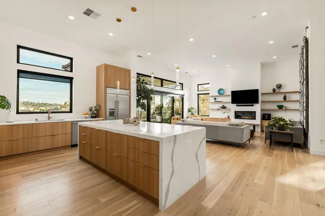 a kitchen with stainless steel appliances granite countertop a refrigerator a sink dishwasher a stove and white cabinets with wooden floor