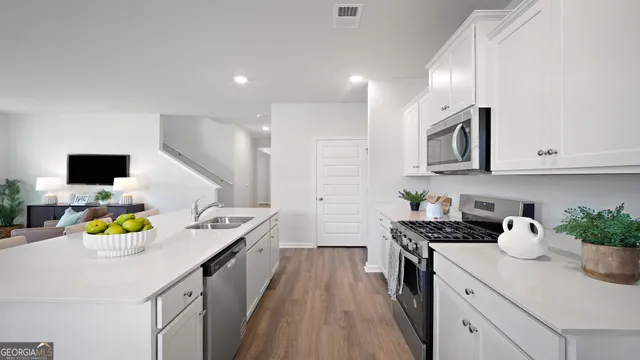 a kitchen with a sink dishwasher stove and microwave with wooden floor