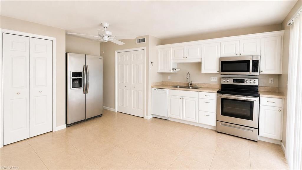 5410 16th Place Southwest, Unit B1 Naples, FL 34116 - Photo 6 of 26 a kitchen with stainless steel appliances white cabinets and a refrigerator