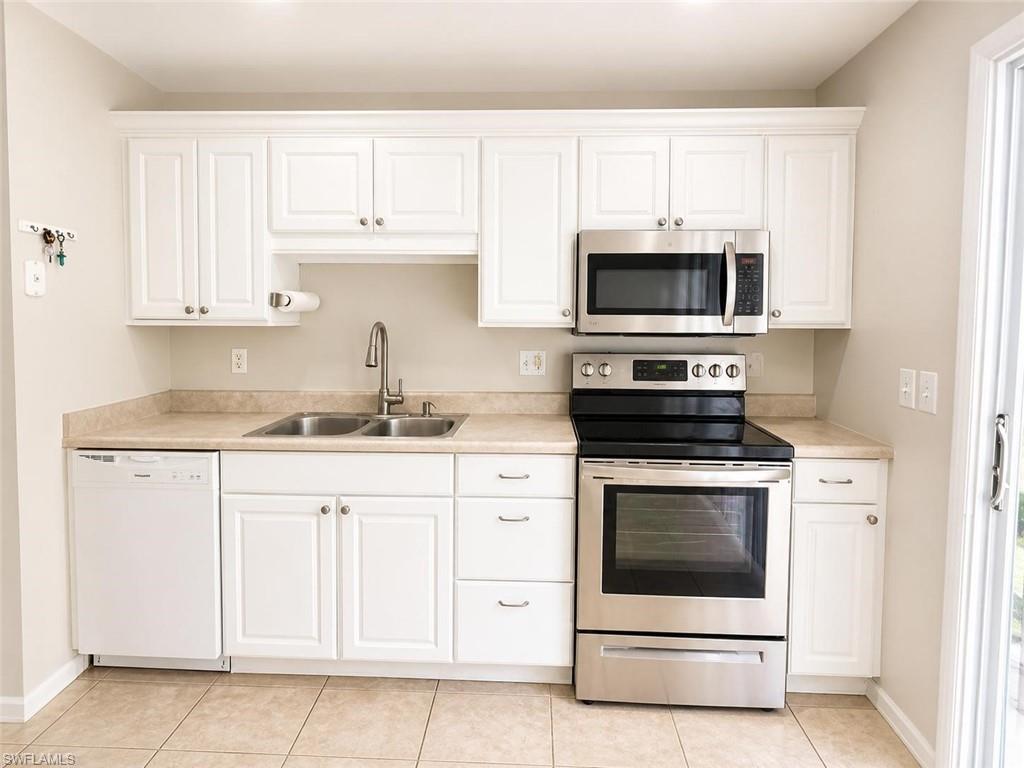 5410 16th Place Southwest, Unit B1 Naples, FL 34116 - Photo 10 of 26 a kitchen with granite countertop white cabinets white stainless steel appliances and a sink