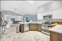 a kitchen with stainless steel appliances granite countertop a stove top oven a sink dishwasher a dining table and chairs with wooden floor