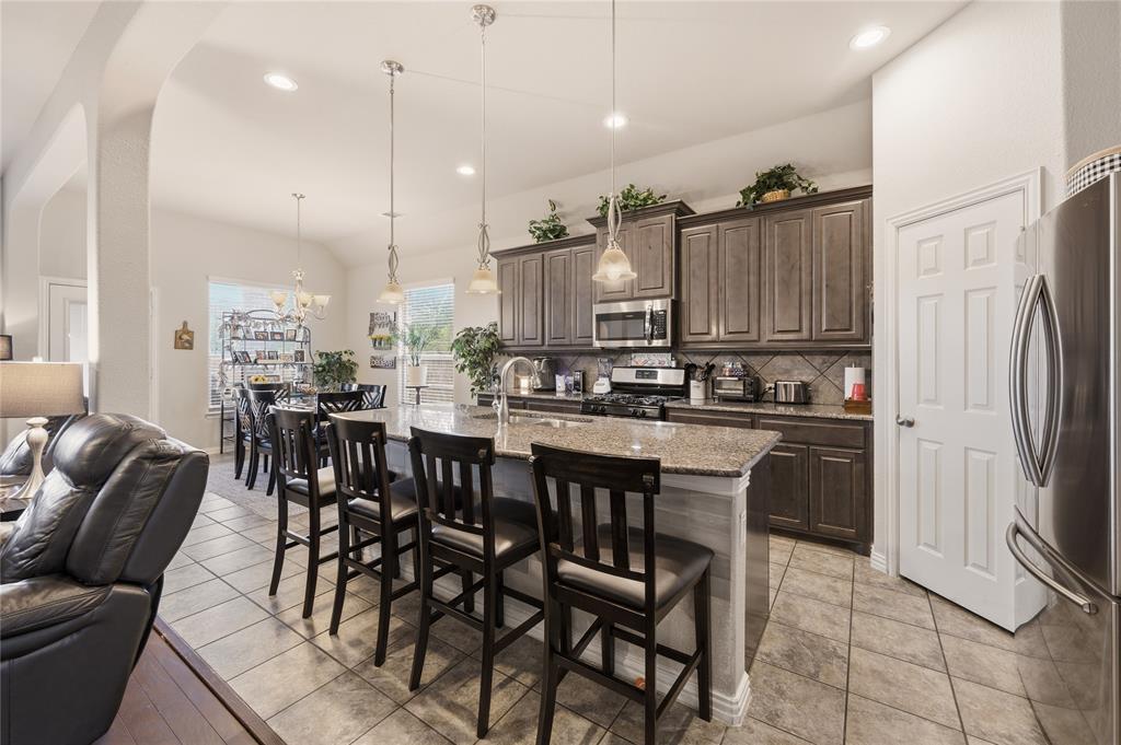 140 Chestnut Road Waxahachie, TX 75165 - Photo 10 of 26 Spacious kitchen featuring an expansive island with seating, granite countertops, tile flooring, and dark wood cabinetry