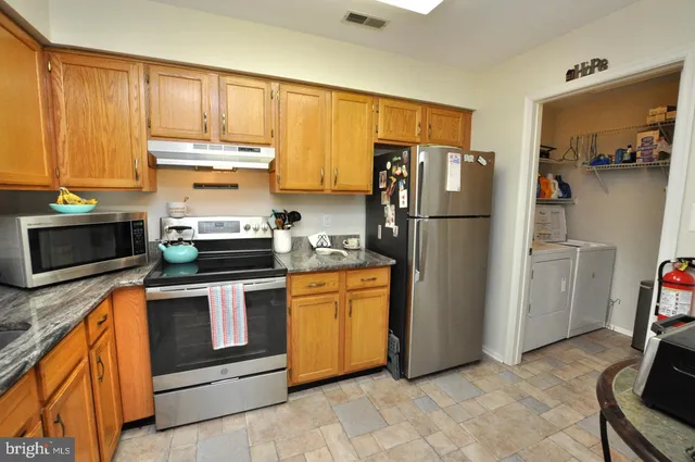 a kitchen with stainless steel appliances granite countertop a refrigerator stove and microwave
