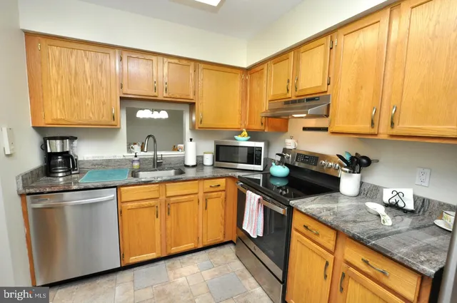 a kitchen with stainless steel appliances granite countertop a sink stove and cabinets