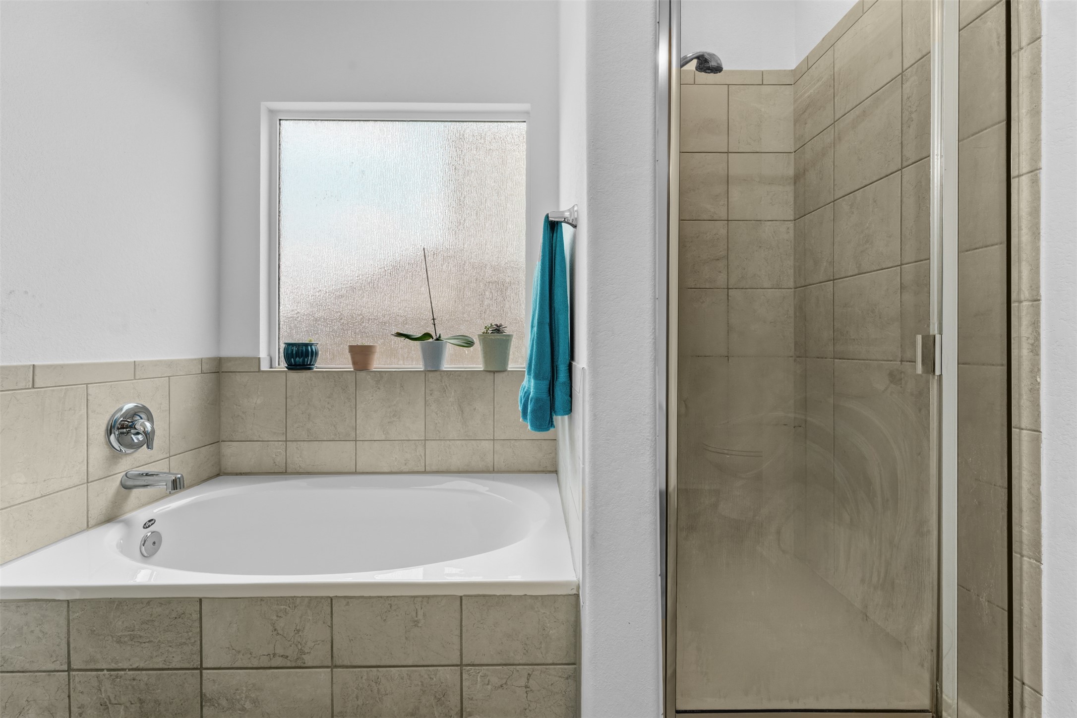 413 Perfect World Loop Jarrell, TX 76537 - Photo 20 of 39 A deep soaking tub sits beneath a privacy window, adjacent to a tiled walk-in shower.