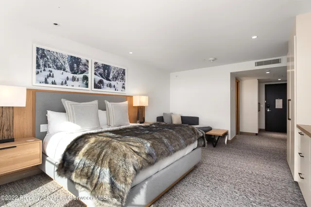 a spacious bedroom with a bed a couch and large window