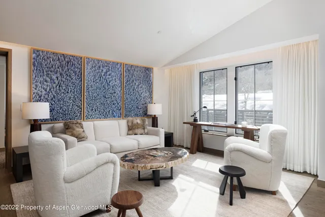 a living room with furniture a flat screen tv and a floor to ceiling window