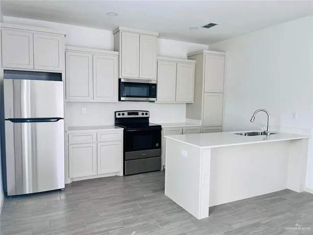 a kitchen with cabinets stainless steel appliances and wooden floor