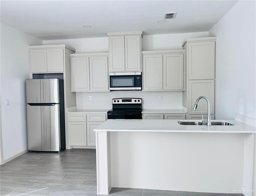 12610 North 33rd Lane, Unit 2 Edinburg, TX 78541 - Photo 3 of 11 a kitchen with a refrigerator a sink and a stove