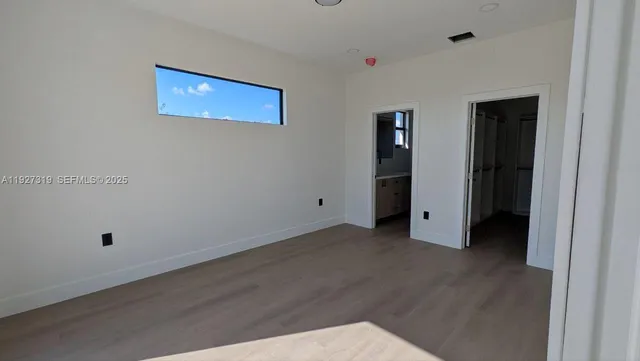 a view of an empty room with wooden floor and closet