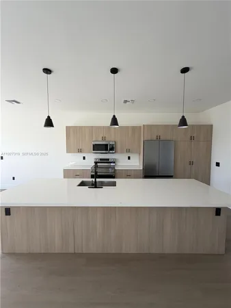 a large kitchen with stainless steel appliances a large counter top a stove and a refrigerator