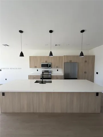 a large kitchen with stainless steel appliances a large counter top a stove and a refrigerator