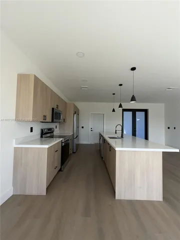 a kitchen with stainless steel appliances a stove top oven a sink a counter top space and cabinets