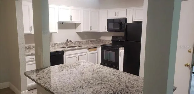 a kitchen with stainless steel appliances granite countertop a stove top oven a refrigerator and a sink