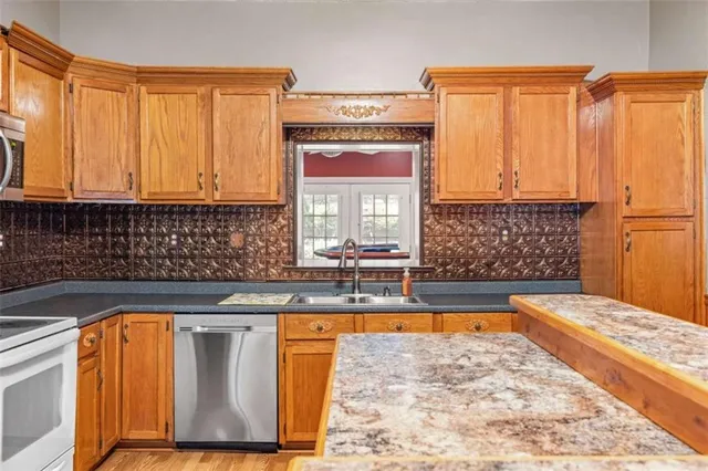a view of a kitchen with kitchen island granite countertop a sink cabinets and a large window