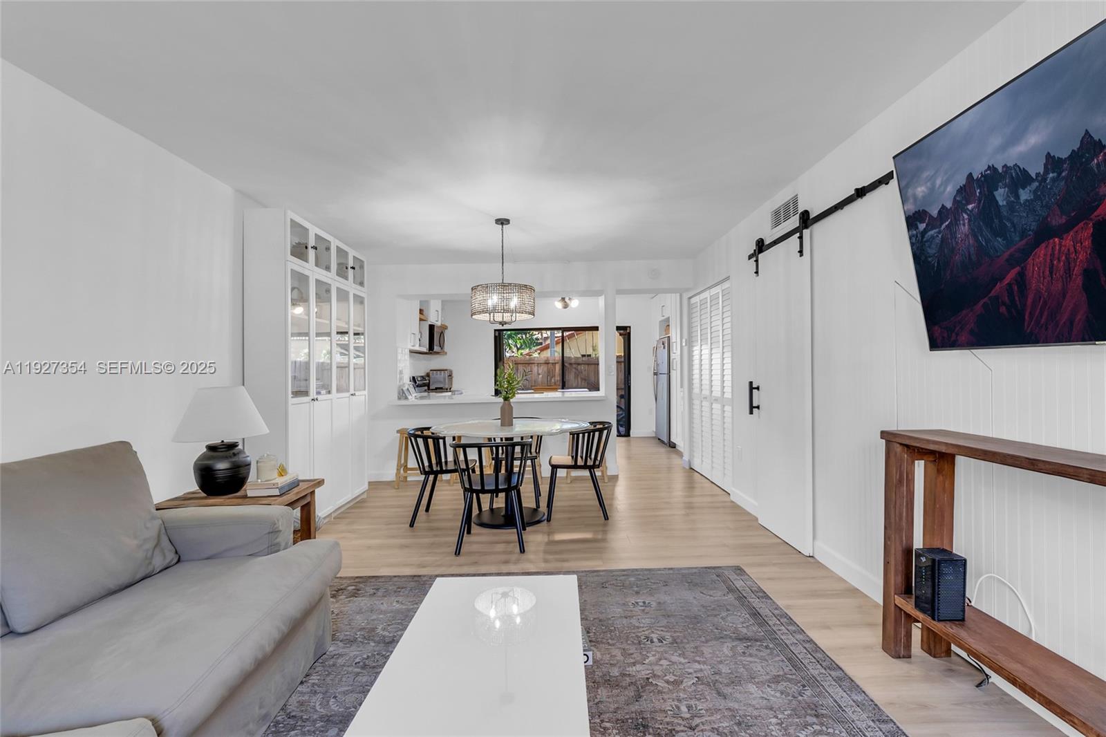 a living room with furniture and a dining table with wooden floor
