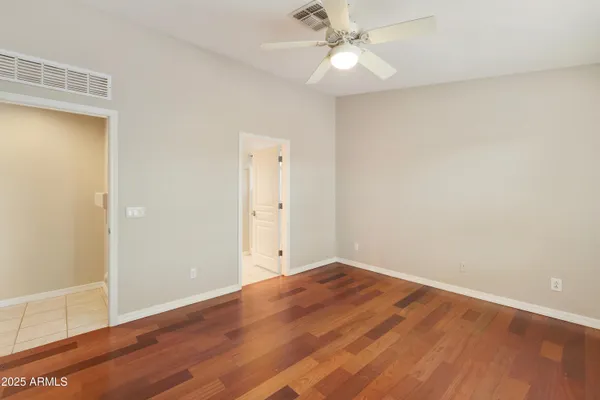 an empty room with wooden floor and fan
