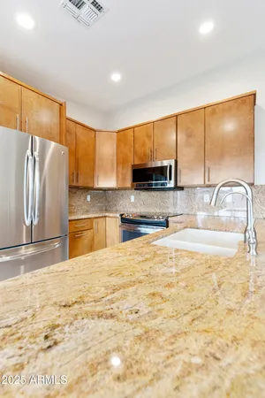a view of a kitchen with kitchen island a sink a counter top space cabinets and stainless steel appliances