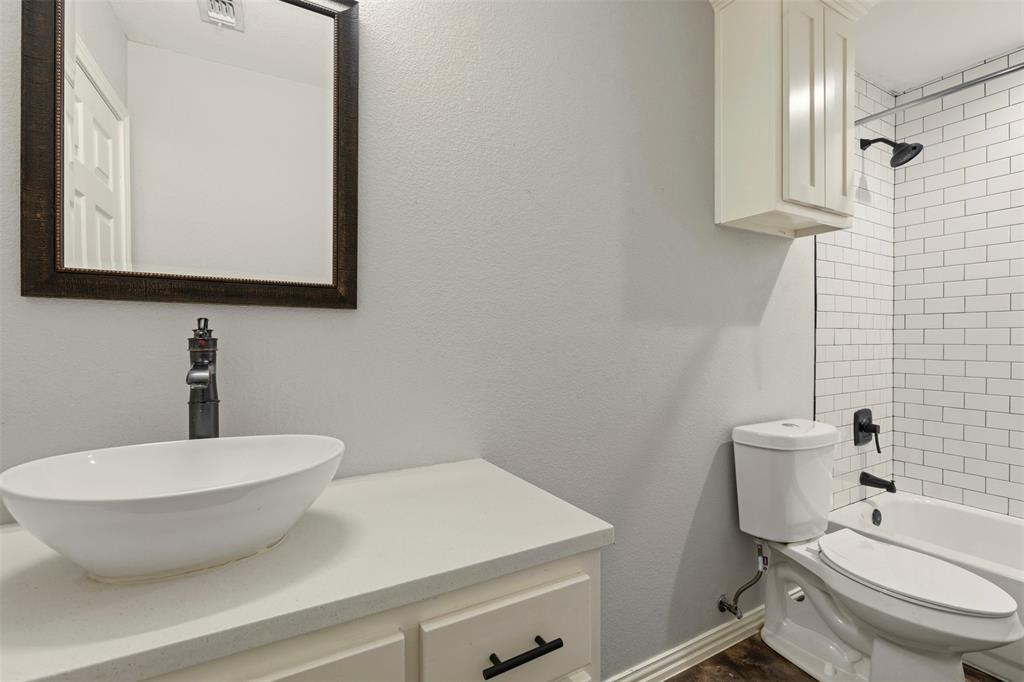 933 Rice Street Denison, TX 75020 - Photo 13 of 21 a bathroom with a toilet sink and mirror