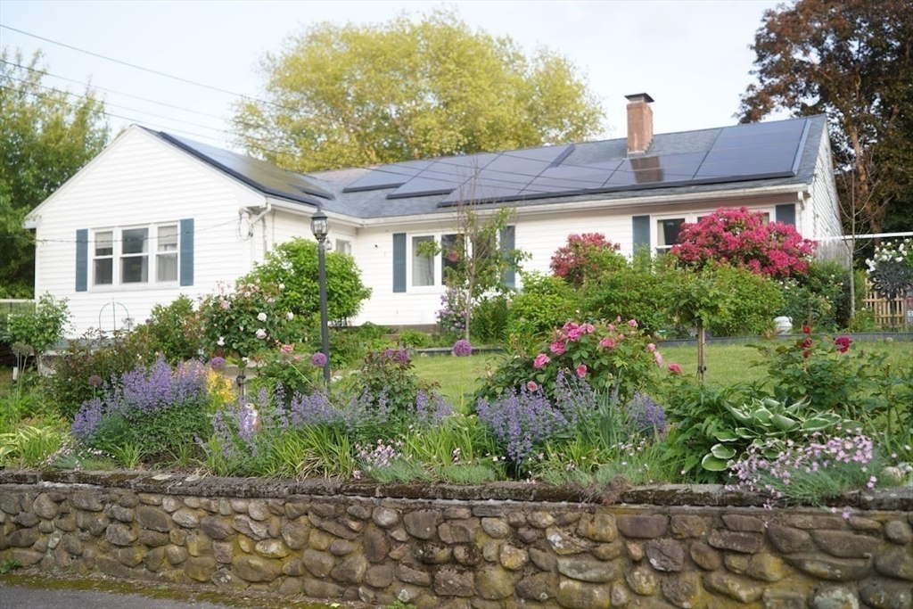 a front view of house and yard with beautiful flowers