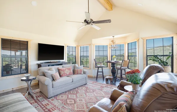 a living room with furniture large window and wooden floor