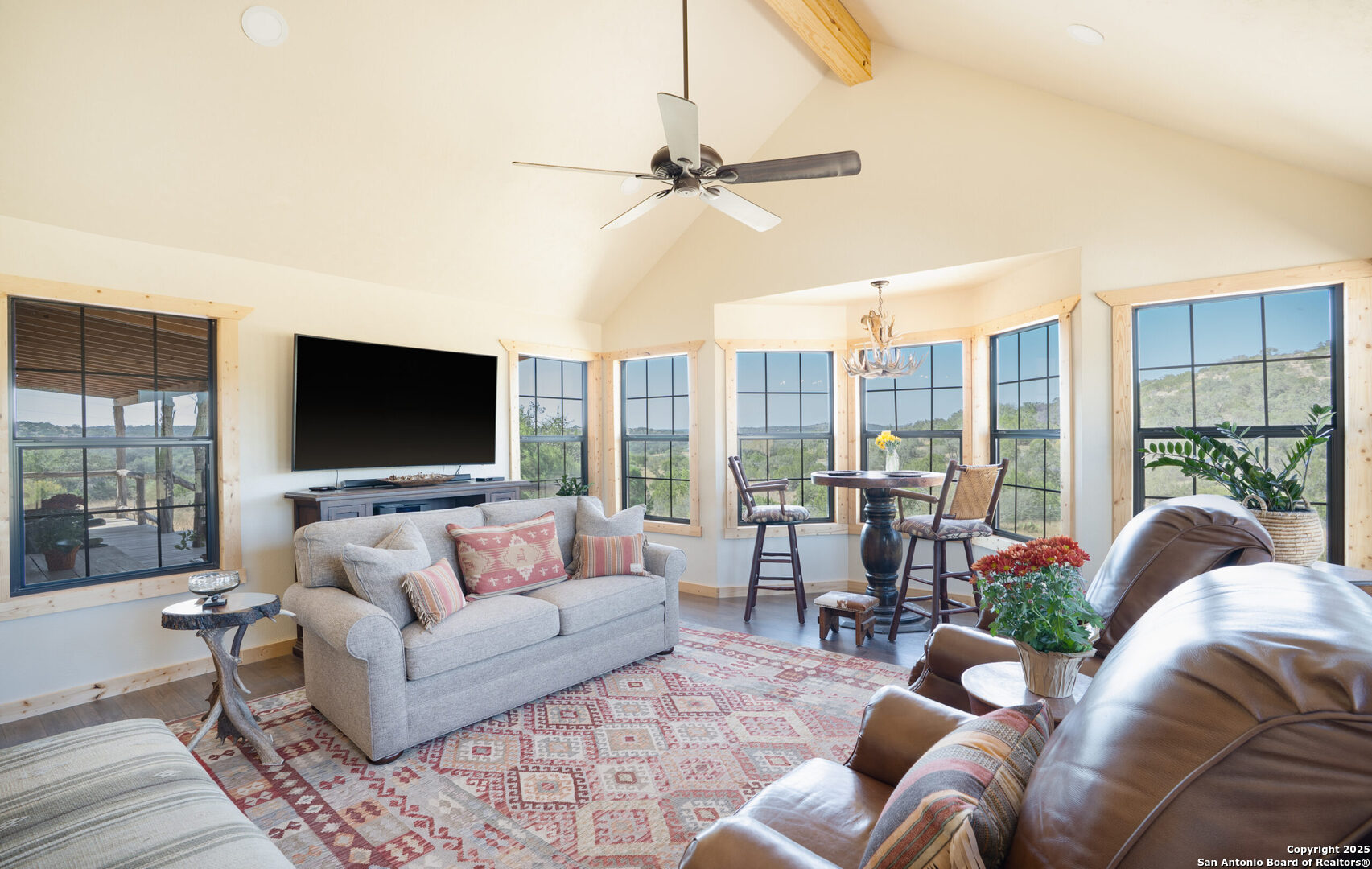 300 County Road 550 Rocksprings, TX 78880 - Photo 13 of 32 a living room with furniture floor to ceiling window hardwood floor and a flat screen tv