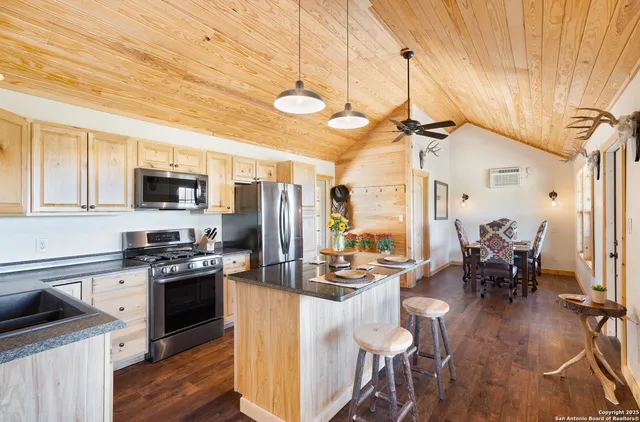 a kitchen with kitchen island granite countertop a stove top oven a sink dishwasher a dining table and chairs with wooden floor