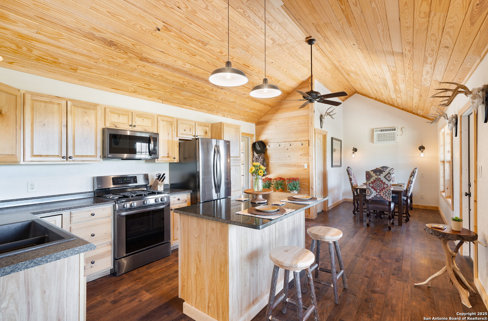 300 County Road 550 Rocksprings, TX 78880 - Photo 5 of 32 a kitchen with stainless steel appliances kitchen island granite countertop a stove top oven a sink a dining table and chairs with wooden floor