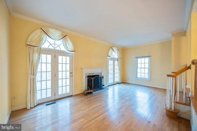 an empty room with wooden floor fireplace and windows